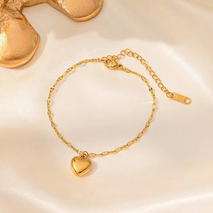 Détail d'un bracelet pendentif cœur doré avec gravure K18 sur maillons délicats en feuilles