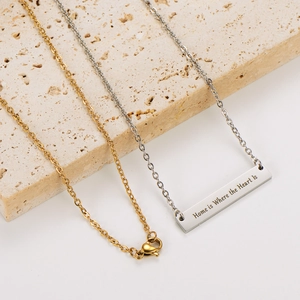 Vista macro de un colgante de barra rectangular con grabado Home is Where the Heart Is