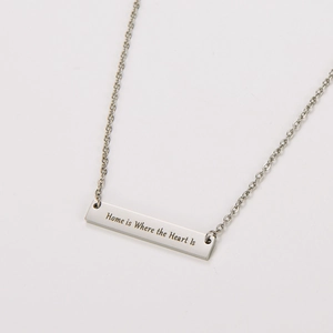 Vista detallada del collar de barra de acero con grabado Home is Where the Heart Is