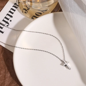 Detailansicht eines silbernen Kreuzanhängers mit feiner Kette auf eleganter Dekoration