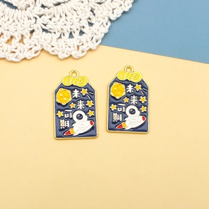 Detailansicht eines Omamori-Anhängers mit Astronauten-Motiv und chinesischem Text.