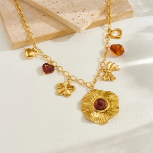 Close-up of vintage gold necklace with resin heart and bow charms on stone plate