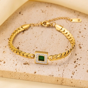 Detail view of gold-plated bracelet with square emerald green stone and zircon inlay