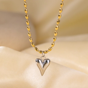 Detailed close-up of mixed silver heart pendant and gold bead chain on champagne satin