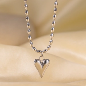 Macro shot of polished heart pendant necklace on soft satin with oval bead chain