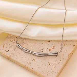 Minimalist silver irregular curved pendant necklace on elegant beige travertine base