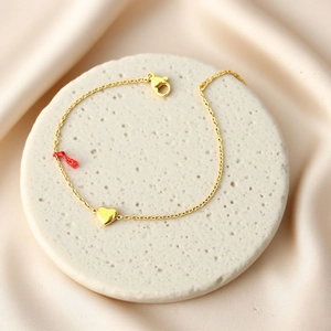 Elegant gold titanium steel heart pendant bracelet on a white textured stone surface