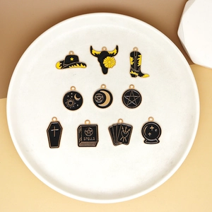 Detail view of various black and gold enamel tarot charms on a white plate.