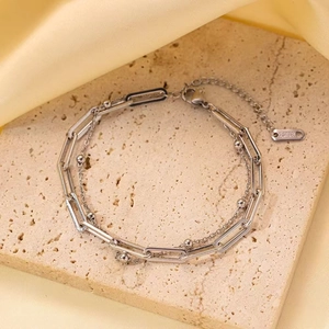 Double-layered stainless steel paperclip and bead chain bracelet on a beige stone surface