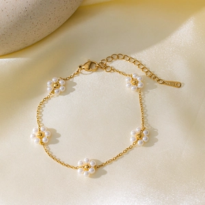 Elegante bracciale in acciaio al titanio dorato con delicati fiori di perle bianche da donna