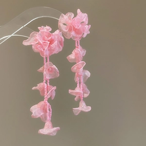 Close-up of pink chiffon flower and bead tassel earrings for a sweet vacation look