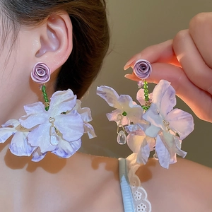 Primo piano di orecchini pendenti a fiore in tessuto viola con accenti di cristallo