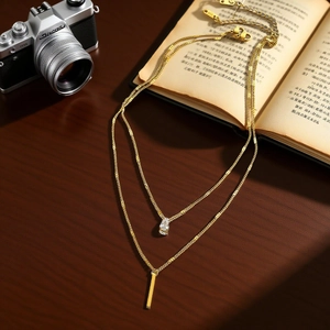 Collana a doppio strato in acciaio al titanio dorato con zircone a goccia e barra