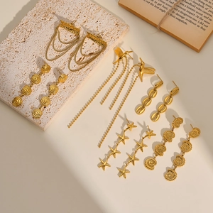 Macro view of gold stainless steel drop earrings with shell and starfish motifs.