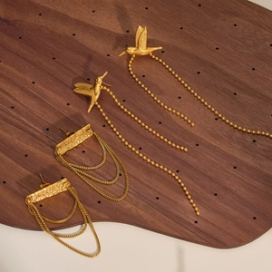Detailed view of gold-tone stainless steel tassel earrings with hummingbird design
