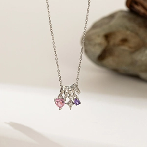 Detailed shot of silver necklace with pink heart, purple stone and star pendants