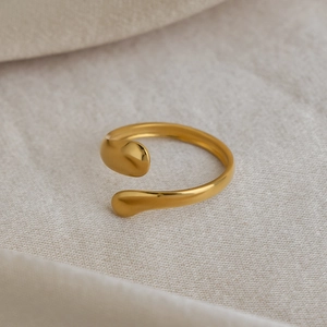 Detail of 18K gold plated teardrop open ring on soft beige textured fabric