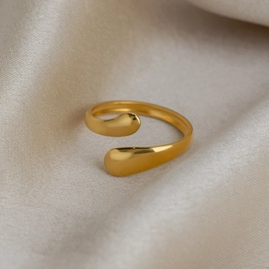Macro shot of 18K gold plated teardrop open ring on champagne silk fabric background
