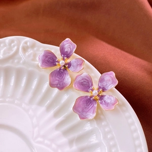 Gros plan de boucles d'oreilles fleurs mauves vintage avec perles sur assiette blanche