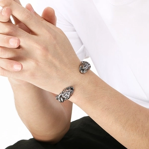 Detalle de brazalete abierto con cabeza de león plateado para hombre en la muñeca