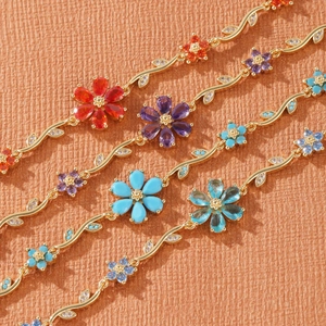 Close-up of golden floral bracelets with colorful petals and vine-shaped links with zircons