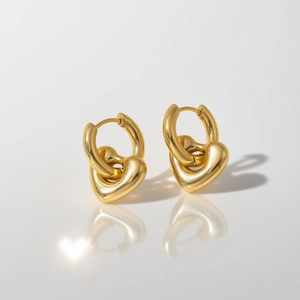 Minimalistische Herz-Ohrringe aus 18k Gold auf weißer Reflexionsfläche mit Herz-Schatten