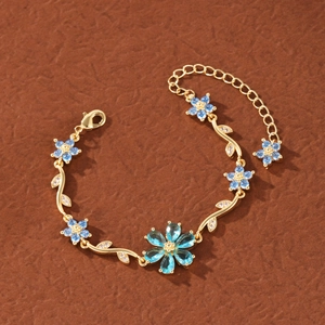 Detailed shot of golden flower bracelet with blue crystals and zircon-encrusted leaves