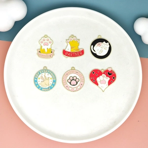 Close-up view of colorful cartoon cat claw and kitty enamel charms on a white ceramic plate.