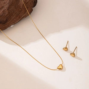 Minimalist 18K gold titanium steel heart necklace and earrings set on stone background