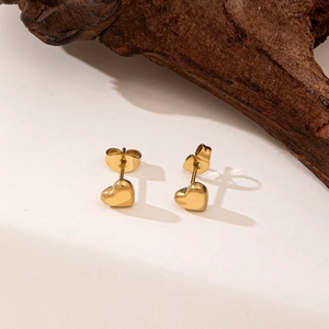Minimalist 18K gold-plated heart stud earrings on a rustic wooden decorative stand