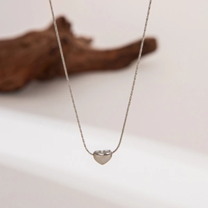 Close-up of a minimalist silver heart pendant on a fine cable chain with polished finish