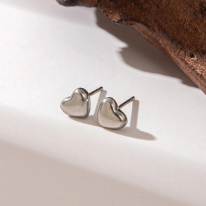 Detailed close-up of heart-shaped silver earrings on a textured background with shadows