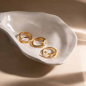 Dettaglio di tre anelli in acciaio inossidabile placcati oro 18K con zirconia e pietre