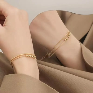 Double-layered 18k gold plated snake chain bracelet with five round beads on wrist
