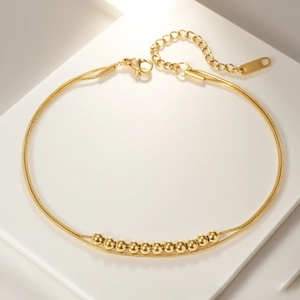 Elegant 18k gold double-layer bracelet with snake chain and round beads on white stand