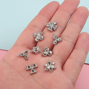 Macro detail view showing various stainless steel DIY jewelry charms held in a hand