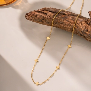 Élégant collier doré avec cinq breloques étoiles à quatre branches sur fond de bois