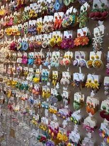 Close-up of colorful handmade woven flower earrings on display wall
