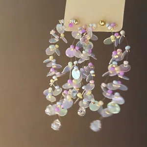 Close-up of iridescent sequin tassel earrings with colorful beads and crystal drops