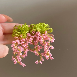 Close-up detail view of pink and green handmade beaded floral cluster drop earrings.