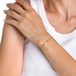 Minimalist gold heart and heartbeat ECG bracelet for women on a model's wrist