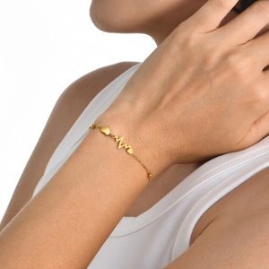 Minimalist gold stainless steel heart and heartbeat charm bracelet on woman's wrist