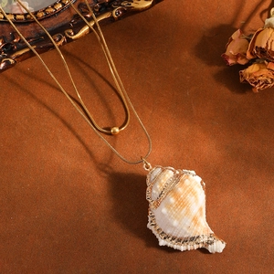 Detailed view of natural seashell pendant on gold double-layered snake chain