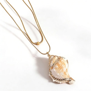 Close-up of a double-layer conch shell pendant necklace on a gold snake chain