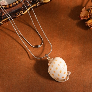 Close-up of double-layered stainless steel necklace with spotted conch shell pendant