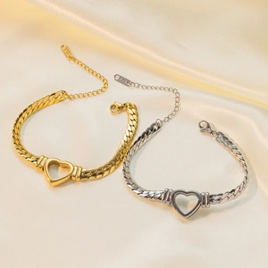 Gold and silver stainless steel heart necklaces with curb chains on silk background