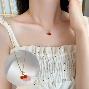 Collier élégant en chaîne dorée avec pendentifs doubles cerises rouges sur modèle