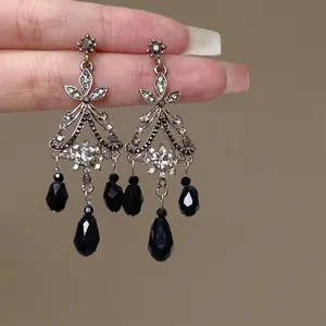 Détail de boucles d'oreilles pendantes style palais rétro avec perles noires et cristaux