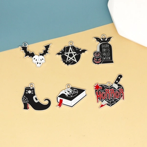 Vue détaillée des breloques d'Halloween en émail avec chauves-souris et pierres tombales.