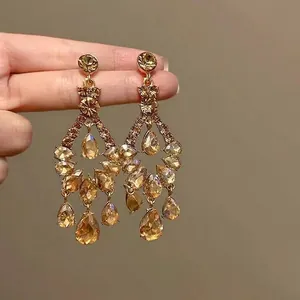 Vue détaillée de boucles d'oreilles rétro dorées avec cristaux gouttes champagne.